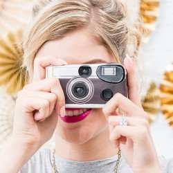 Femme qui prend une photo avec l'appareil photo jetable rétro